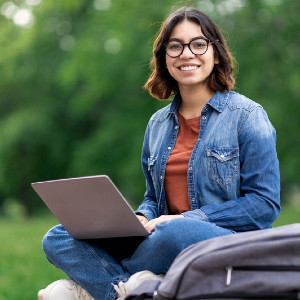 young woman in denim jacket with laptop in outdoor setting