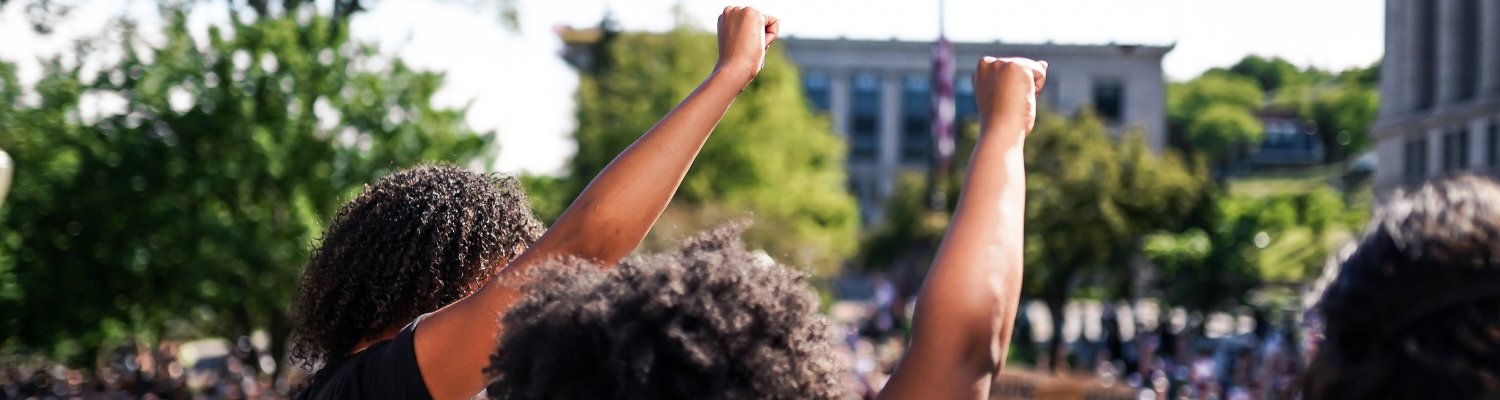 Two Black women raise their fists in the air in solidarity