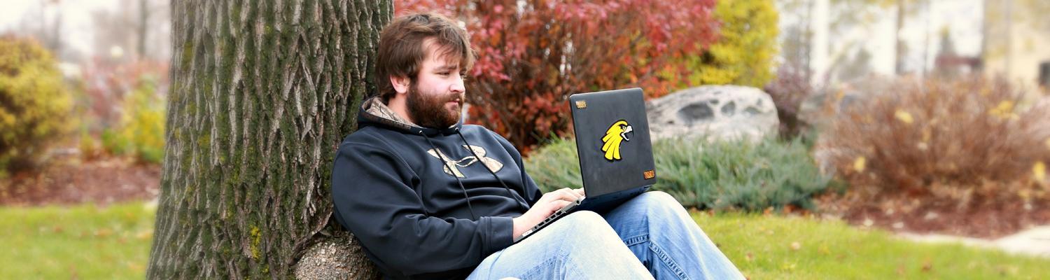 man with laptop against tree