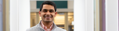 Man, smiling, wearing a grey jacket and red plaid shirt