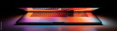 colorfully lit half open laptop computer with black background
